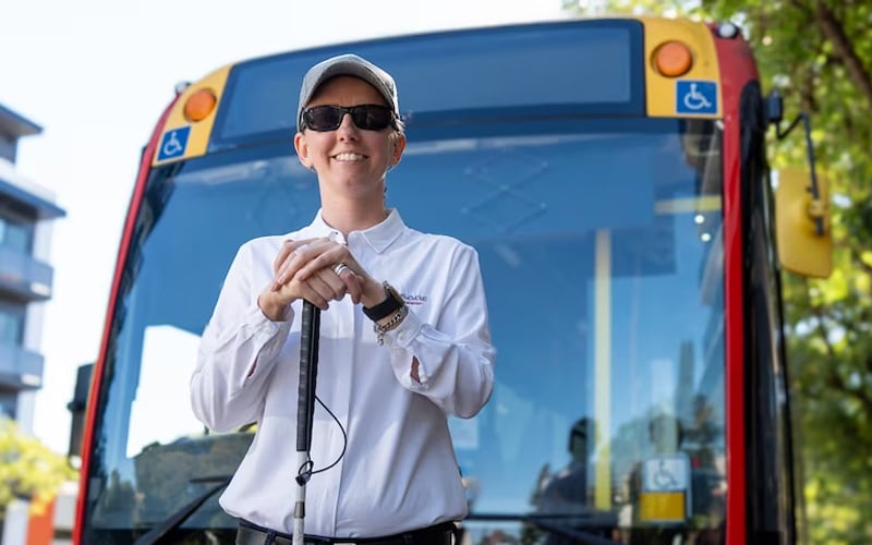 Cassie Hames in front of bus holding cane